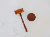 Drewniany młotek sędziowski i krążek na białym tle.