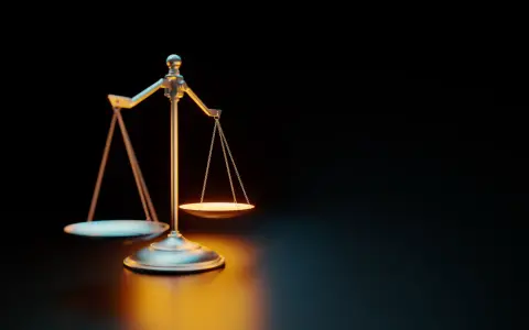 Waga szalkowa na ciemnym tle, oświetlona ciepłym światłem.