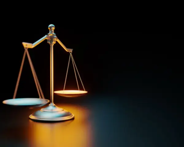 Waga szalkowa na ciemnym tle, oświetlona ciepłym światłem.