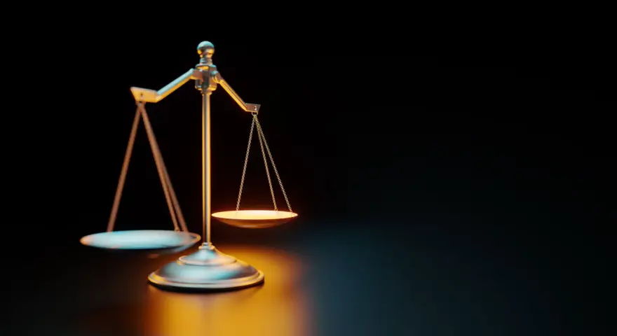 Waga szalkowa na ciemnym tle, oświetlona ciepłym światłem.